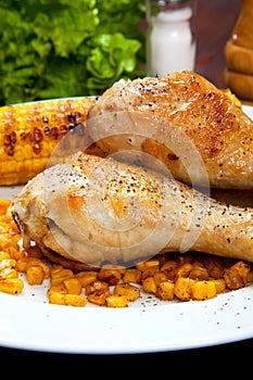 Chicken thigh with a boundary of corn cob and salad