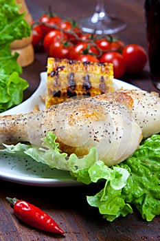 Chicken thigh with a boundary of corn cob and salad