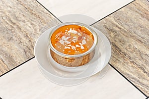 Chicken tikka masala curry served in a traditional metal bowl of Pakistani restaurant on a marble table