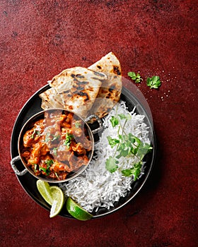 Chicken tikka masala spicy curry meat food Butter chicken, rice and naan bread on red vine dark background. Traditional Indian