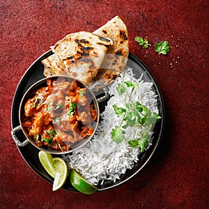 Chicken tikka masala spicy curry meat food Butter chicken, rice and naan bread on red vine dark background. Traditional Indian