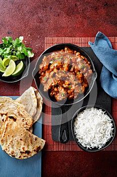 Chicken tikka masala spicy curry meat food Butter chicken, rice and naan bread on red vine dark background. Traditional Indian