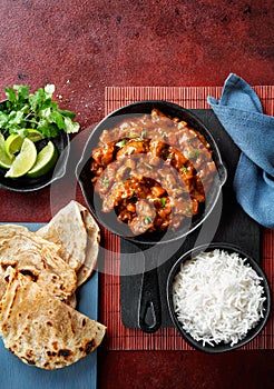 Chicken tikka masala spicy curry meat food Butter chicken, rice and naan bread on red vine dark background. Traditional Indian