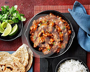 Chicken tikka masala spicy curry meat food Butter chicken, rice and naan bread on red vine dark background. Traditional Indian