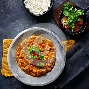 Chicken tikka masala spicy curry meat food in marbre plate with rice and spices on dark gray background