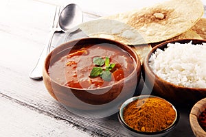 Chicken tikka masala spicy curry meat food in pot with rice and naan bread. indian food on table