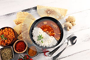 Chicken tikka masala spicy curry meat food in pot with rice and naan bread. indian food on table