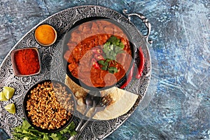 Chicken tikka masala spicy curry meat food in pot with rice and naan bread. indian food on table