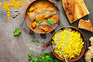 Chicken tikka masala with yellow rice and naan on a dark brown background. Indian food. Top view, copy space, flat lay