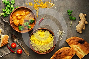 Chicken tikka masala with yellow rice and naan on a dark brown background. Indian food. Top view, copy space, flat lay