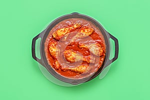 Chicken tomato stew pot, above view on a green background