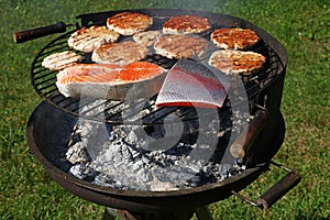 Chicken or turkey burgers and salmon fish on grill