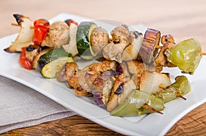 Chicken and vegetable kabobs on white plate