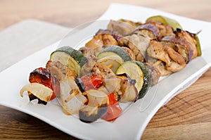 Chicken and vegetable kabobs on white plate