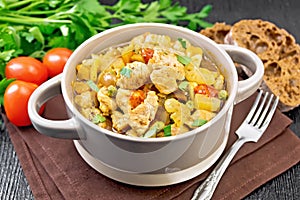Chicken with vegetables and peas in saucepan on table