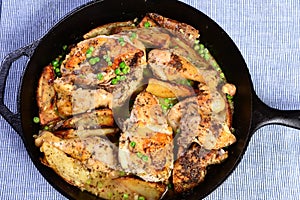 Chicken Vesuvio in a cast iron skillet served with potatoes and peas