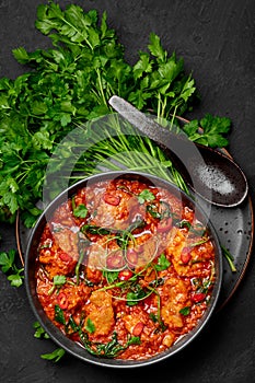 Chicken Vindaloo with spinach in black bowl on dark slate table top. Indian cuisine meat chilli curry dish. Asian food