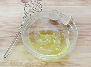 Chicken whites in a glass bowl on a wooden background.