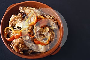 Chicken wings baked in oven with sweet pepper and onions on black background. Top view. Copy space