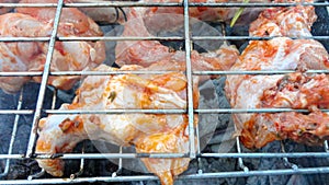 Chicken wings barbecue on a metal grill on hot coals.