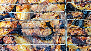 Chicken wings barbecue on a metal grill on hot coals.