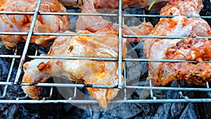 Chicken wings barbecue on a metal grill on hot coals.