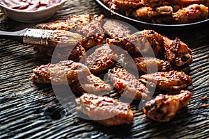 Chicken wings barbeque in a cast iron baking dish with BBQ sauce