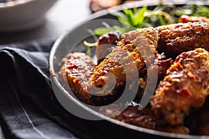 Chicken wings barbeque in a cast iron baking dish with BBQ sauce and rosemary