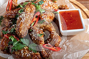 Chicken wings in soy sauce. Served for beer. Sprinkle with sesame seeds. Next to chili pepper sauce and tomatoes. On a wooden