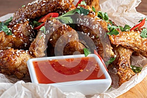 Chicken wings in soy sauce. Served for beer. Sprinkle with sesame seeds. Next to chili pepper sauce and tomatoes. On a wooden