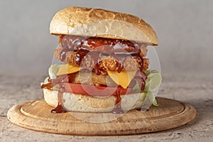 chickenburger centred on wooden plate on a gray background photo