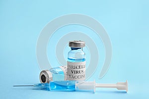 Chickenpox vaccine and syringe on light blue. Varicella virus prevention