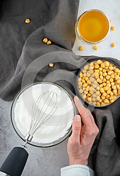 Chickpea aquafaba. Egg replacement. Vegan cooking concept. Men hands whippe whisk chickpeas liquid in glass bowl. chickpea in a