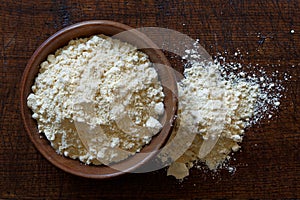 Chickpea flour in dark wooden bowl isolated on dark brown wood f