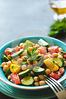 Chickpea salad with tomatoes, cucumber, parsley, onions in a plate, selective focus. Healthy vegetarian food, oriental and