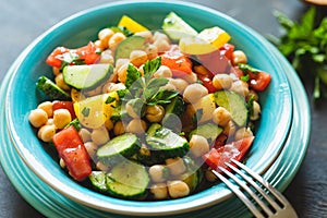 Chickpea salad with tomatoes, cucumber, parsley, onions in a plate, selective focus. Healthy vegetarian food, oriental and