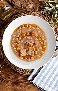 Chickpea stew dish potage - cocido madrileÃ±o. With beef, sausage chorizo, bacon, carrots and olive oil. Rustic appearance.