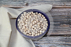 Chickpeas (Cicer arietinum) in a blue bowl, on a wooden table, top view.