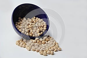 Chickpeas (Cicer arietinum) in a blue crockery bowl isolated on a white background.