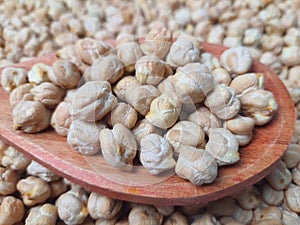 Chickpeas (Cicer arietinum) closeup in a wooden spoon, blurred background, selective focus