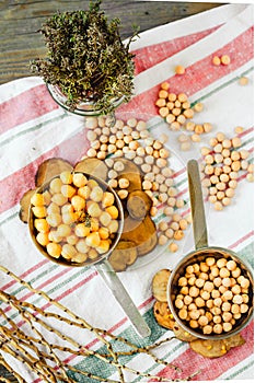 Chickpeas dry and boiled in an iron bowl, thyme. Rustik style background. Top view.