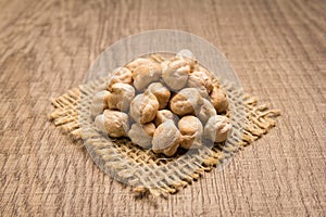 Chickpeas legume. Grains on square cutout of jute. Wooden table.