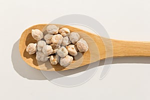 Chickpeas legume. Nutritious grains on a wooden spoon on white b