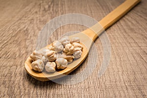 Chickpeas legume. Spoon and grains over wooden table.