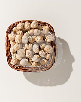 Chickpeas legume. Wicker basket with grains. Top view, hard light. photo