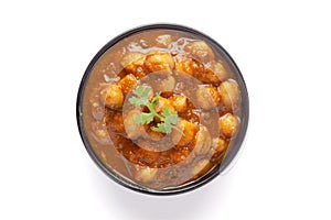Chickpeas masala Spicy chola or chhole curry  garnished with fresh green coriander and ingredients. Served in a black bowl. A