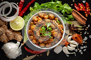 Chickpeas masala Spicy chola or chhole curry  garnished with fresh green coriander and ingredients. Served in a ceramic bowl.