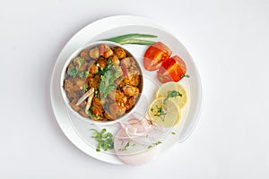 Chickpeas masala Spicy chola or chhole curry  garnished with fresh green coriander and ingredients. Served in a ceramic bowl.