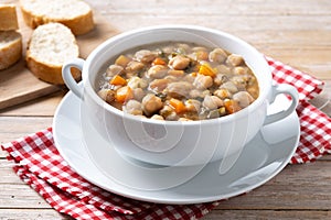 Chickpeas soup with vegetables in bowl on wood