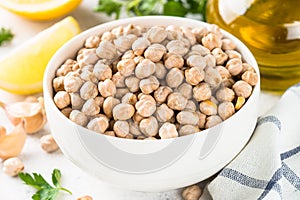 Chickpeas in white bowl at light kitchen table.